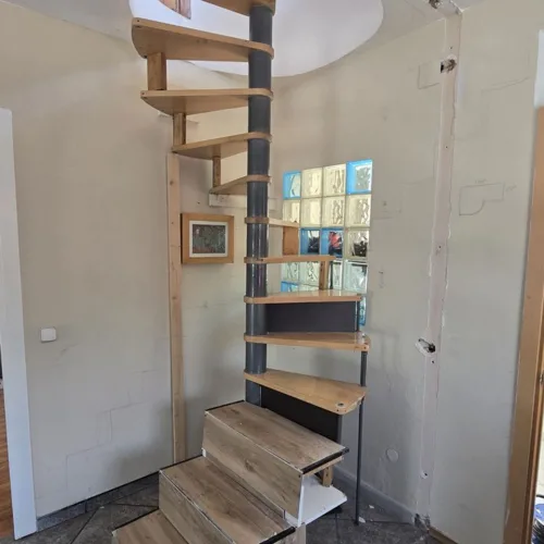 Escalera de caracol metálica con peldaños de madera en una vivienda