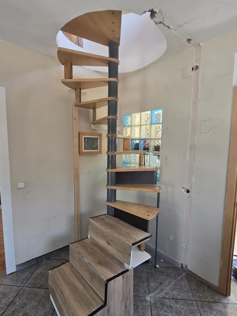 Escalera de caracol metálica con peldaños de madera en una vivienda