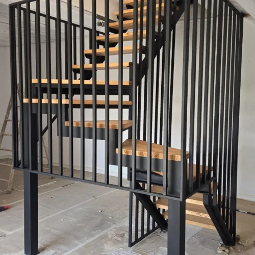 Barandilla de barrotes verticales en una escalera interior de acero y madera